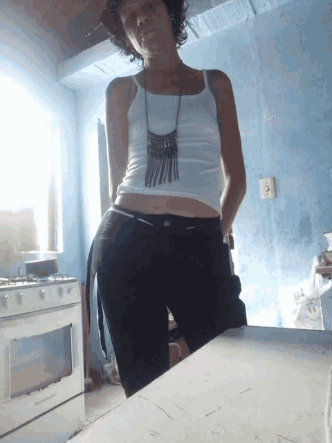 a woman wearing a white tank top and black pants