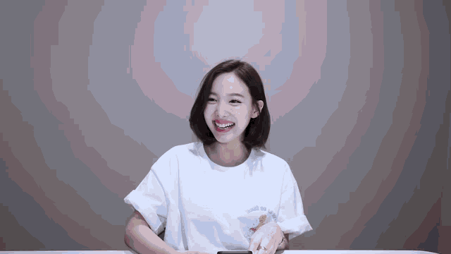 a woman is sitting at a table wearing a white t-shirt with a picture of a bear on it