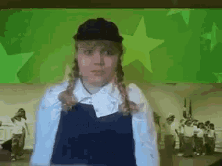 a girl wearing a black hat and overalls is standing in front of a green background