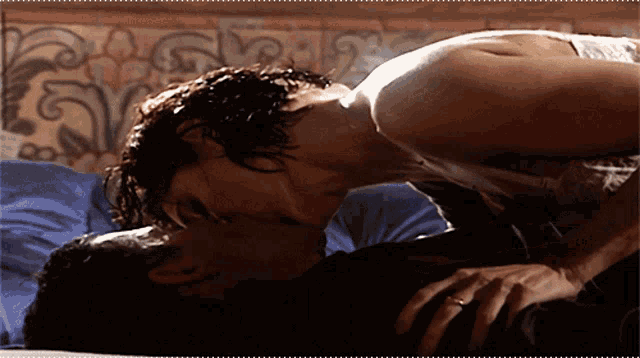 a man and woman kissing on a bed with a floral background
