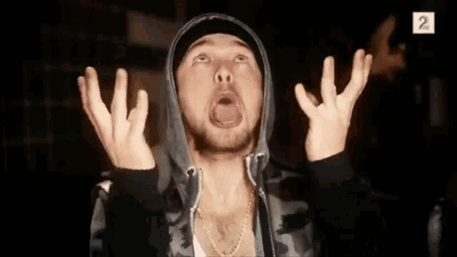 a man in a hooded jacket is making a funny face and the number 2 is on the bottom right