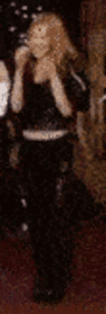 a woman in a black top and black pants is standing in a room .