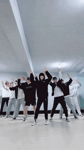 a group of people are standing in a room with their arms in the air