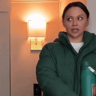 a woman in a green jacket holding a green bottle