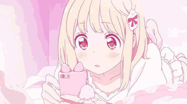 a girl is laying on a bed looking at a cell phone