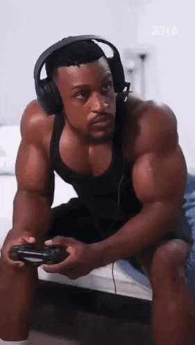 a muscular man wearing headphones is playing a video game on a bed