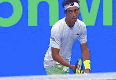 a tennis player wearing a white adidas shirt holds a tennis racket