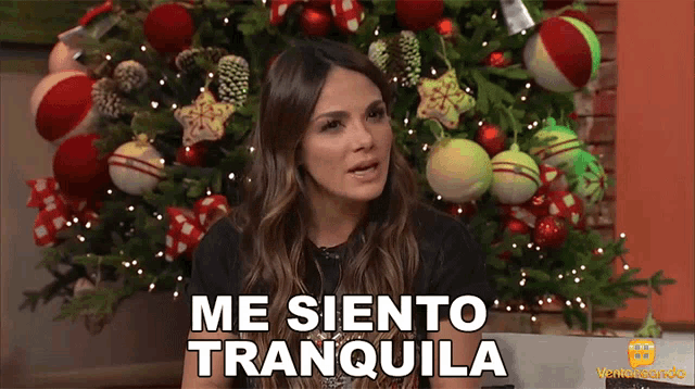 a woman is standing in front of a christmas tree and says me siento tranquila