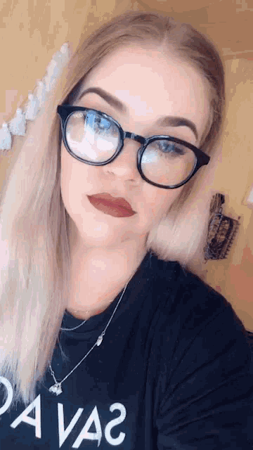 a woman wearing glasses and a black shirt that says " da va "