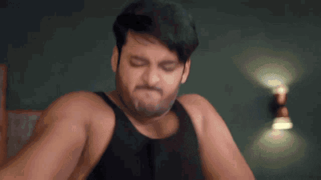 a man with a beard is wearing a black tank top .