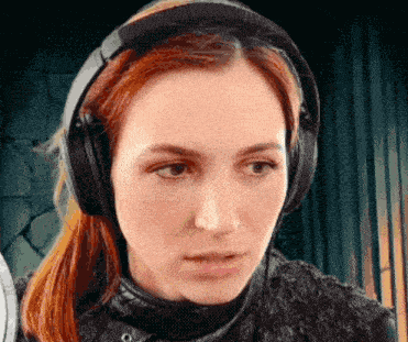 a woman with red hair is wearing headphones and looking at the camera