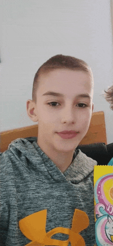 a young boy in a grey under armour hoodie