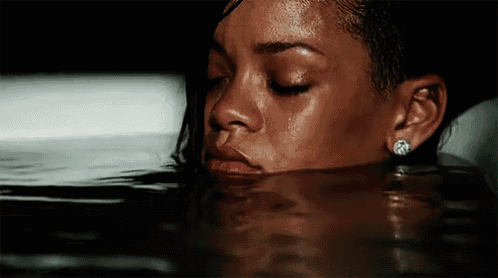 a woman is laying in the water with her eyes closed and a tear running down her face .
