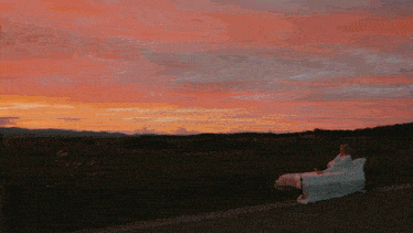 a woman sits on a couch in front of a sunset