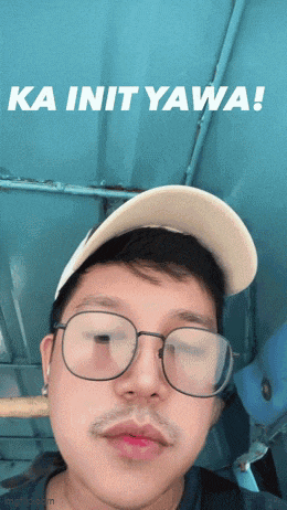 a man wearing glasses and a baseball cap says ka init yawa