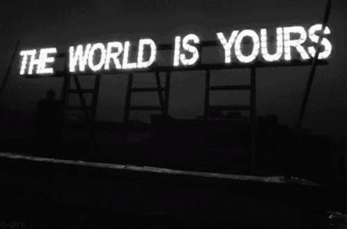 a sign that says the world is yours is lit up in the dark