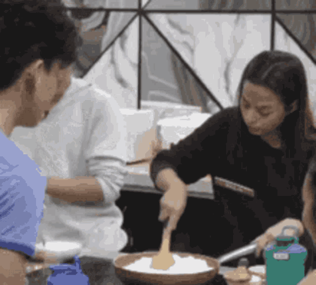 a group of people are cooking in a kitchen with a green water bottle in the foreground