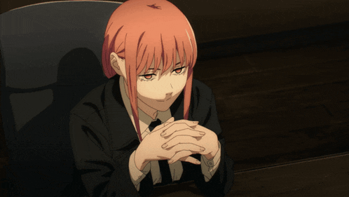 a woman with red hair is sitting at a table with her hands folded