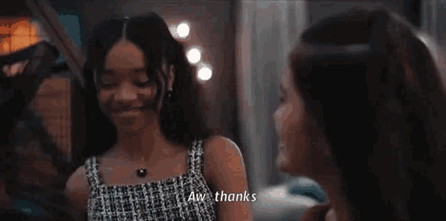two girls are standing next to each other in a room and one of them is talking to the other .