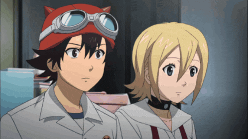 a boy wearing a cat hat and goggles stands next to a girl wearing a choker