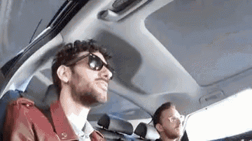 a man wearing sunglasses is sitting in the back seat of a car .