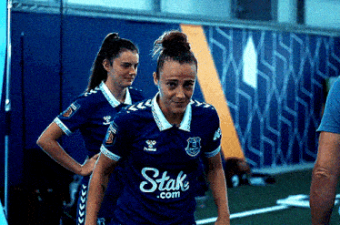a female soccer player wearing a blue shirt that says ' stake.com ' on it