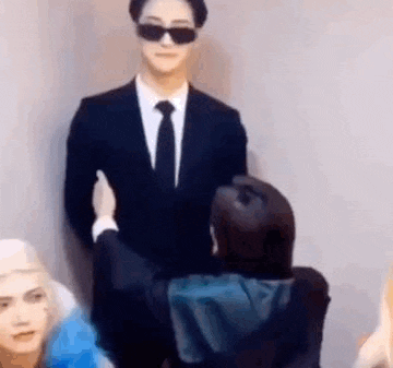 a man in a suit and tie is standing next to a woman wearing sunglasses .