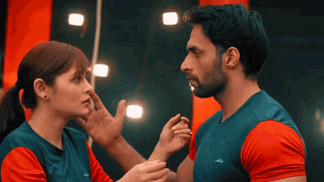 a man and a woman are touching each other 's faces and the man 's shirt has the letter l on it