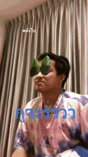 a man wearing a tie dye shirt with a leaf on his eyes