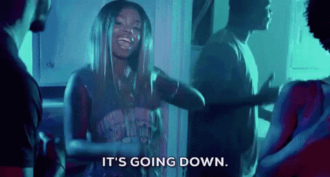 a woman is dancing in a room with a group of people and says `` it 's going down . ''