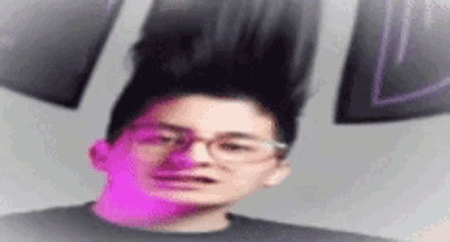 a man with glasses and a bun on his head is standing in front of a wall .