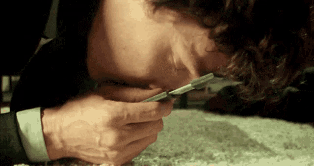 a man is laying on the floor sniffing a piece of paper .