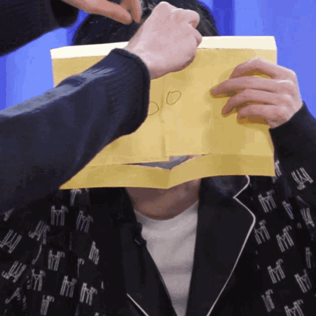 a person covering another person 's face with a piece of paper that says ' do ' on it