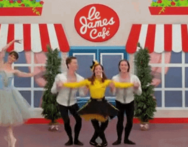 a group of people are dancing in front of a restaurant with a sign that says le james cafe .