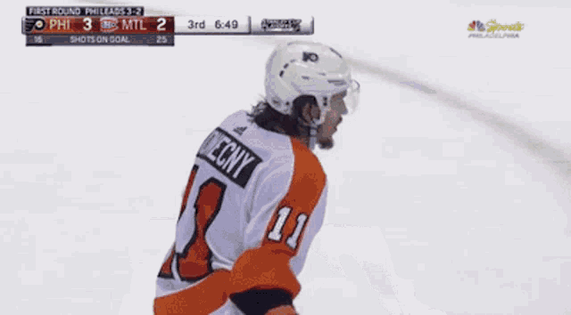 a hockey player with the number 11 on his jersey stands on the ice
