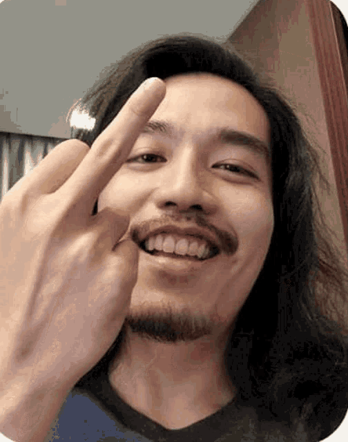 a man with a beard is smiling and giving the middle finger