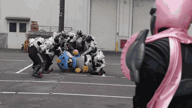 a person in a pink helmet is standing in front of a group of people in costumes