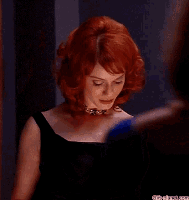 a woman with red hair is wearing a black dress and necklace