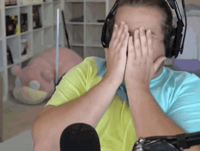 a man covering his face with his hands in front of a microphone