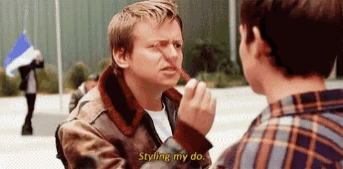a man is brushing another man 's nose with a comb and says `` styling my do '' .