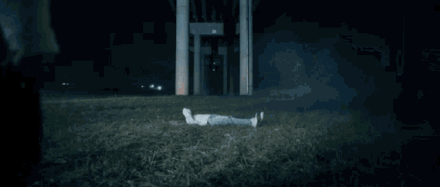a person is laying on the ground in the grass while a group of people look on .