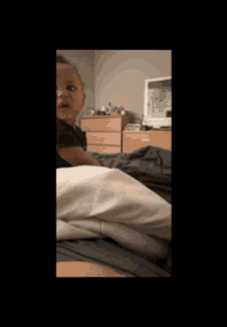 a baby is laying on a bed with a dresser in the background