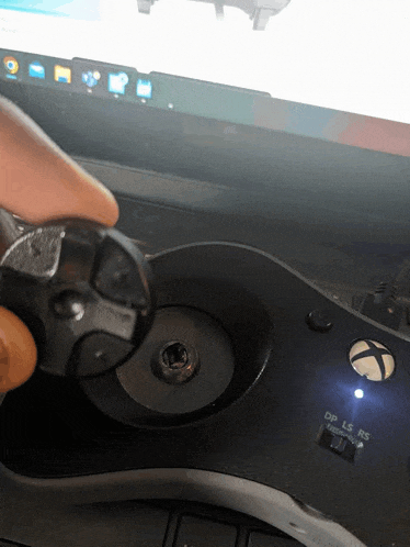 a person is holding a xbox controller in front of a laptop screen