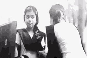 a black and white photo of two girls talking