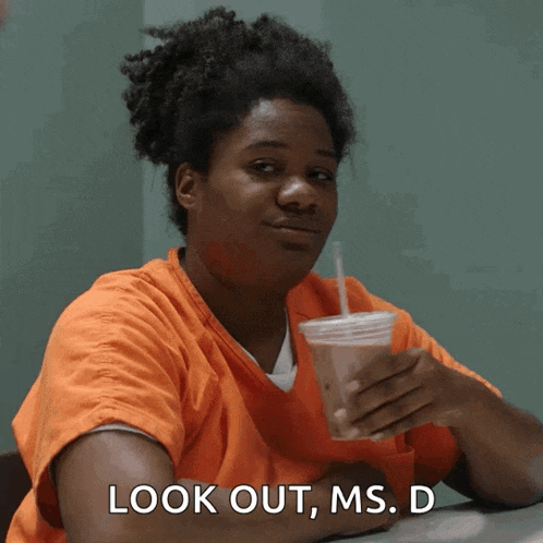 a woman sitting at a table with a drink in her hand and the words look out ms. d above her