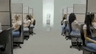 a blurry picture of people sitting in cubicles in an office