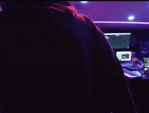 a man in a dark room with purple lights and a monitor that has the number 8 on it