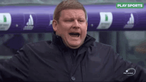 a man in a black jacket is screaming while standing in front of a purple banner that says play sports .