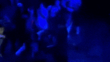 a group of people are dancing in a dark room in a club .