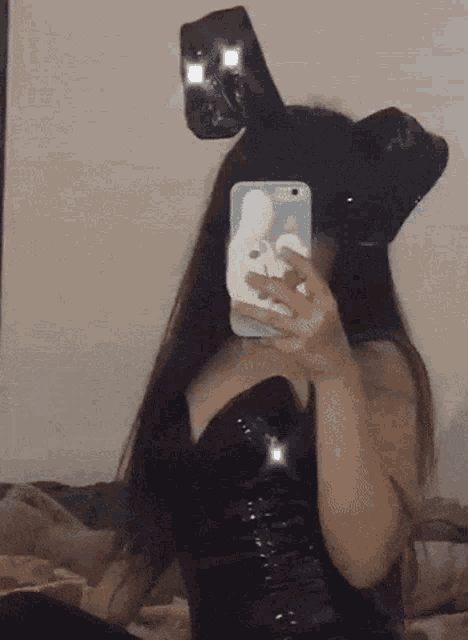 a woman wearing bunny ears is taking a selfie in the mirror .